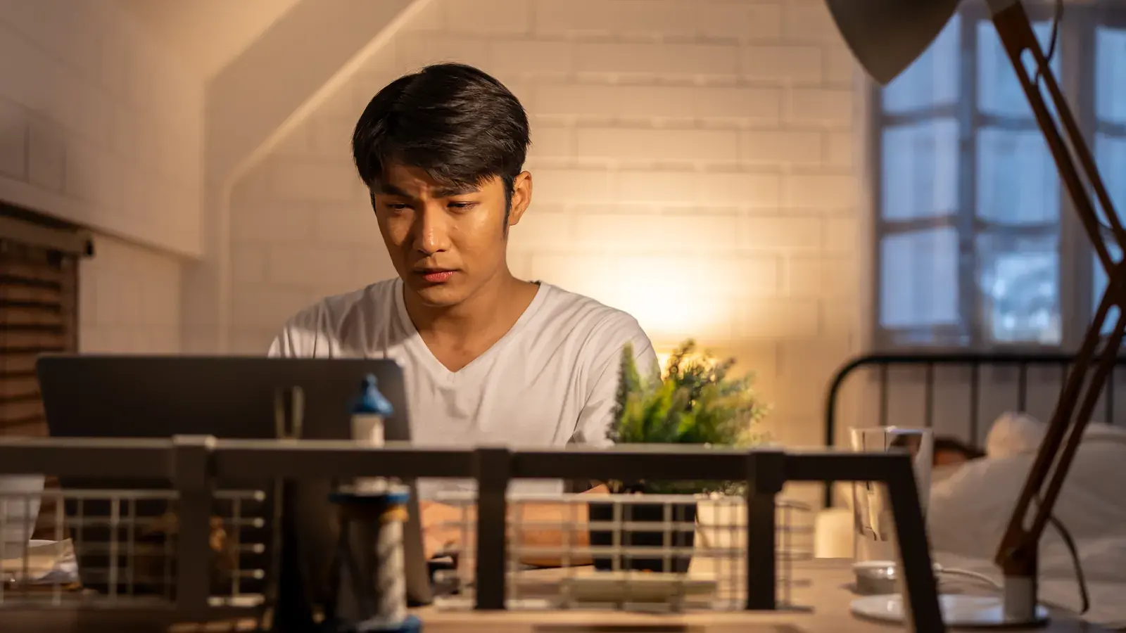 An Indonesian contractor working at a laptop at home in the evening.