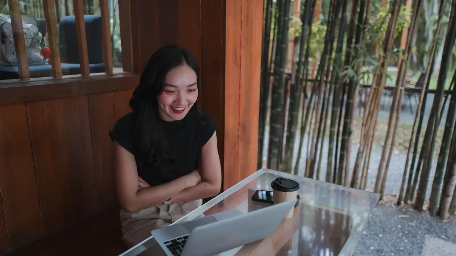 An Indonesian remote worker smiling at a laptop screen during a call.