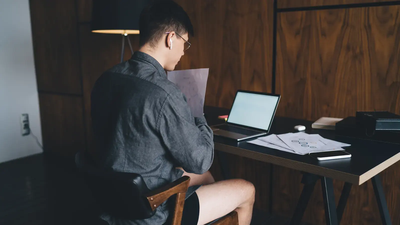 An Indonesian remote worker concentrating at a laptop at a home desk.