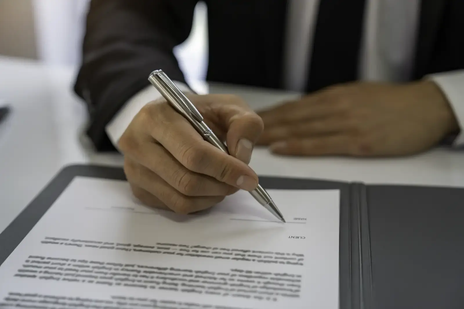 Adult signing legal document in office workplace.