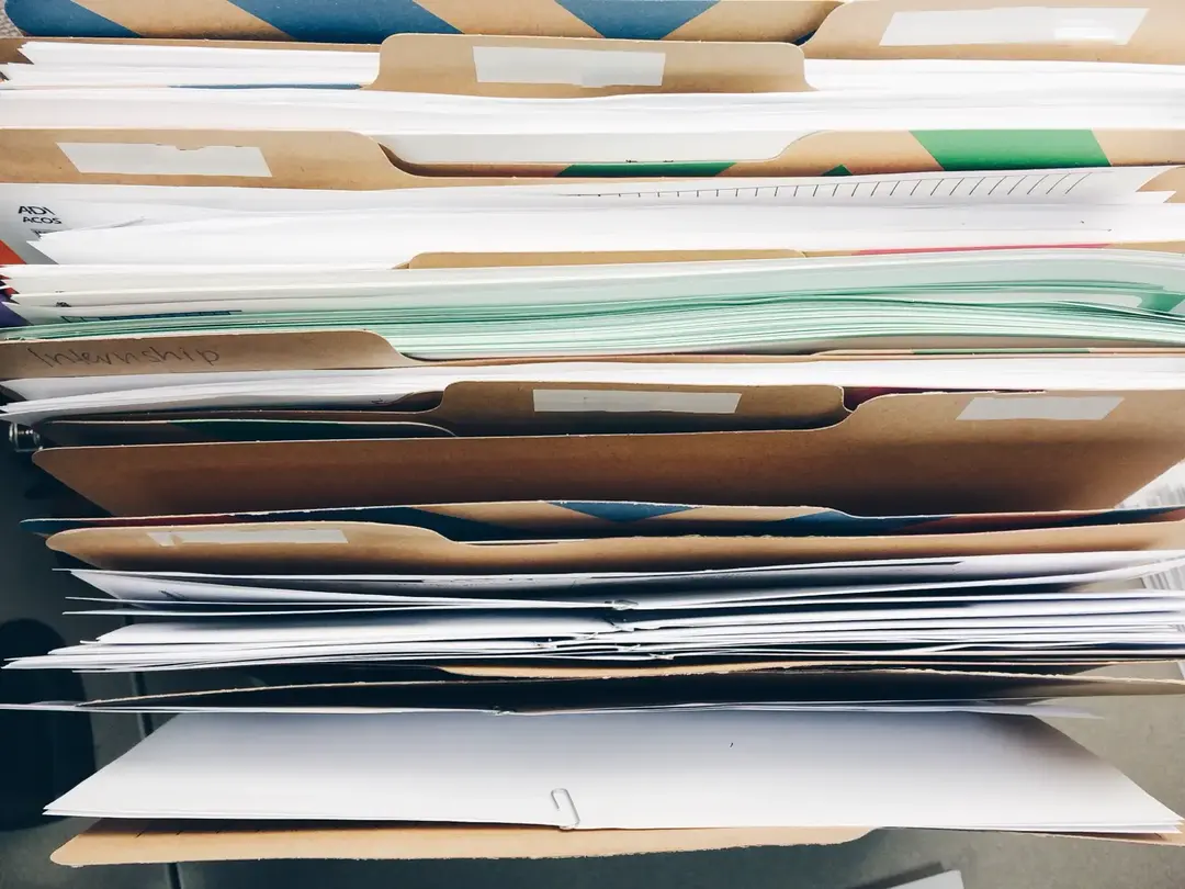 Stacks of administrative files on an office desk.
