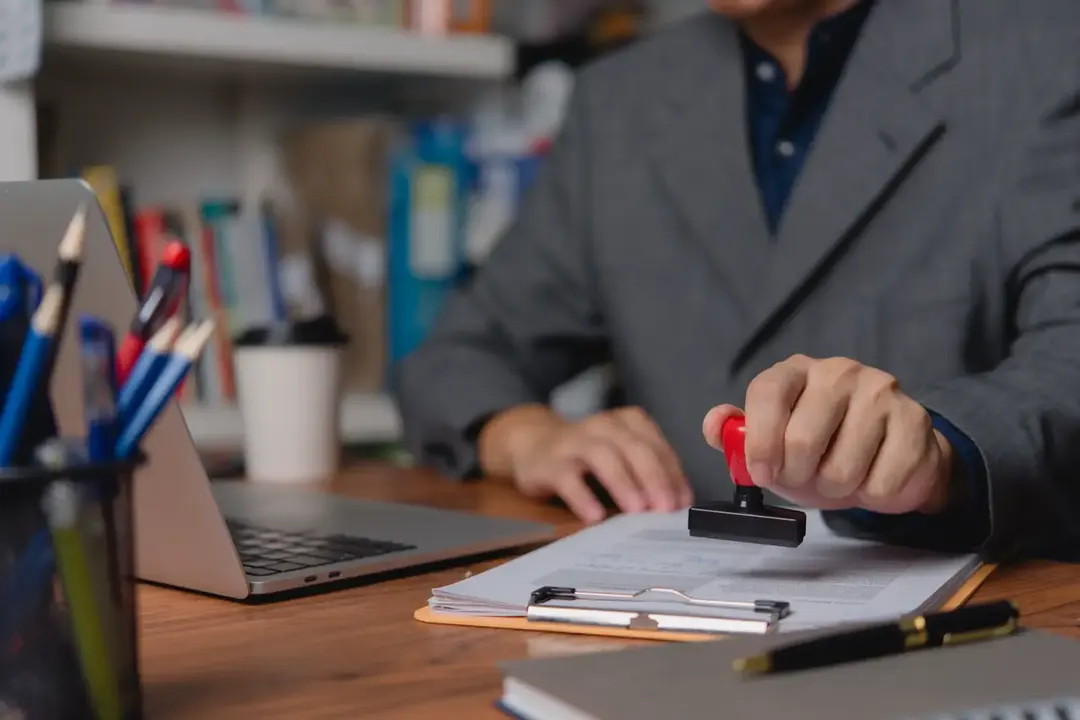 Reviewing and approving printed documents at a desk.