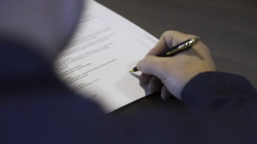 Signing a contract at a desk.