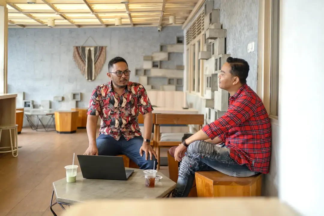 Dua pekerja Indonesia berdiskusi di ruang kerja.