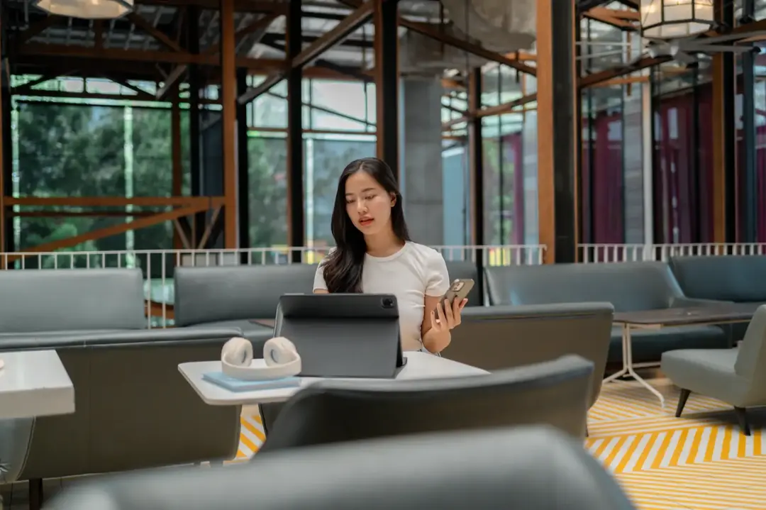Perempuan memakai tablet di ruang kerja modern.