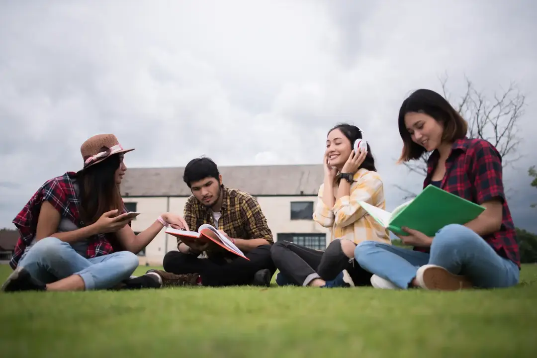 Mahasiswa duduk santai di taman setelah kelas.