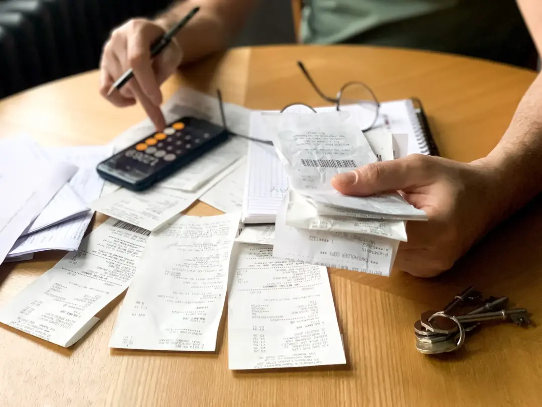 Working through bills and receipts with a pen and calculator.
